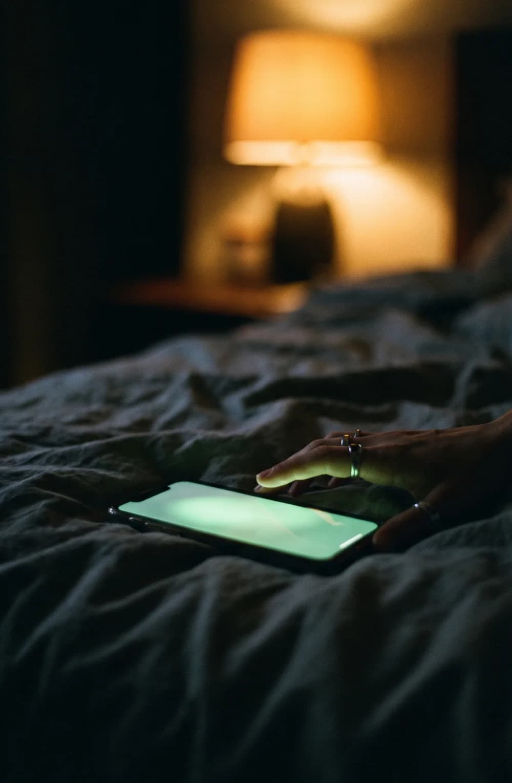 A phone glowing on a bed at night
